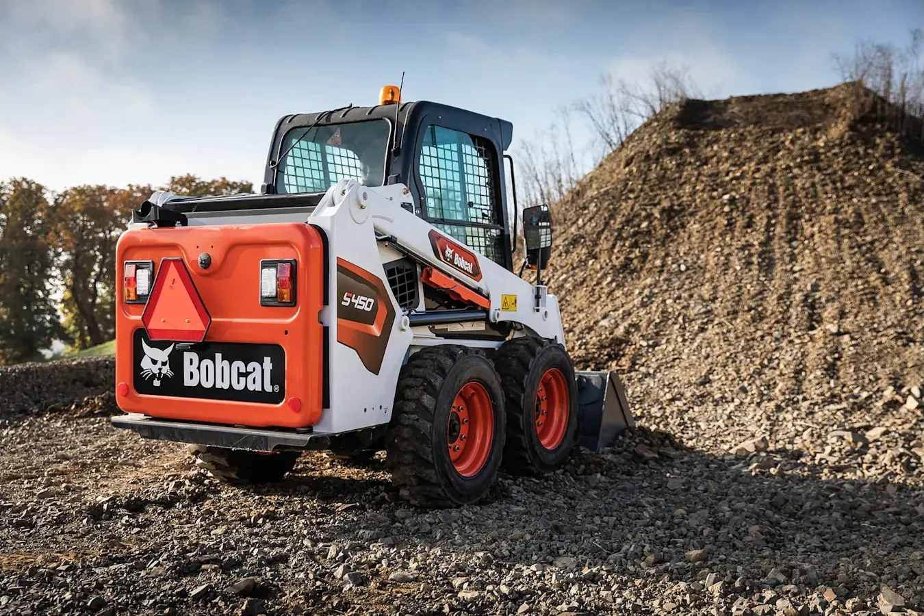 Pala compatta gommata Bobcat S450 vista da dietro su un cumulo di ghiaia